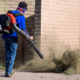 Worker using leaf blower to clear landscape trimmings from walkway
